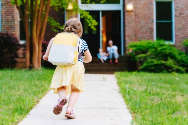 Happy Toddler girl arriving from school-kidhours home from school with a backpack